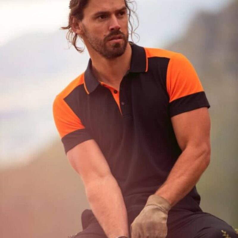 Lifestyle image of man wearing two tone orange and black printer prime polo shirt outside